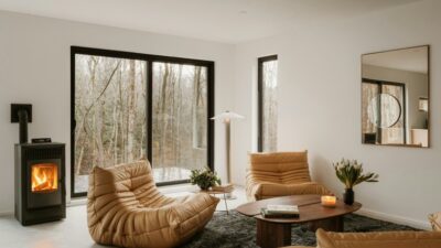 Woonkamer met houtkachel en grote ramen in de herfst